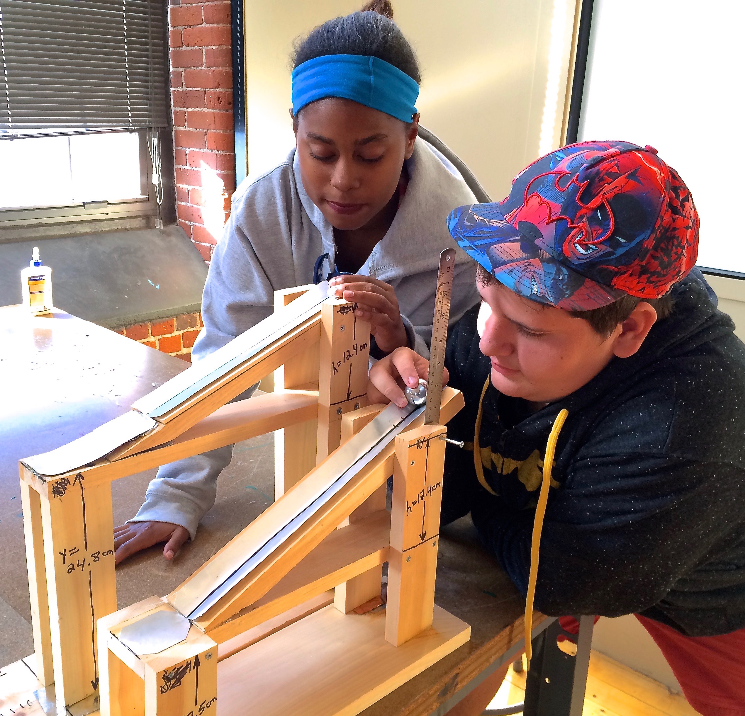 photo of kids doing physics experiment, rolling balls down ramps